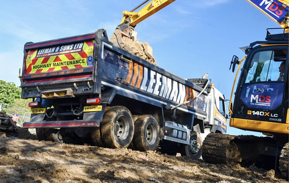 A grab lorry from Leeman & Sons Ltd actively engaged in muck away services at a construction site.