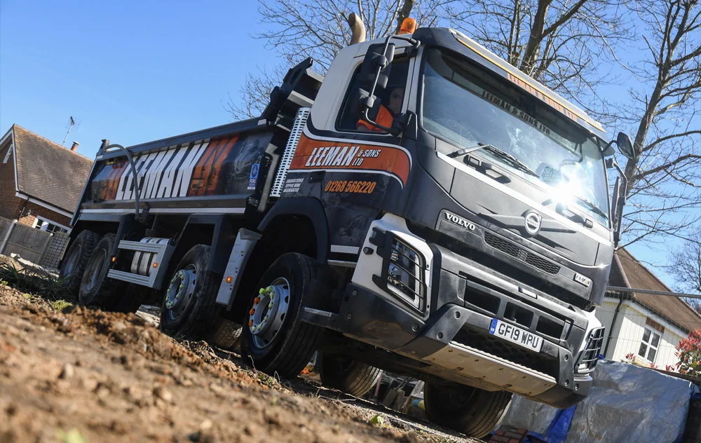 Volvo tipper hire lorry from Leeman and Sons Ltd working on an Essex residential street, highlighting local community services.